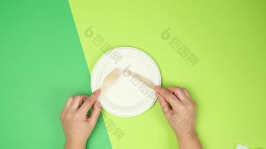 空白色纸板女手持有<strong>一次性</strong>叉刀绿色背景前视图